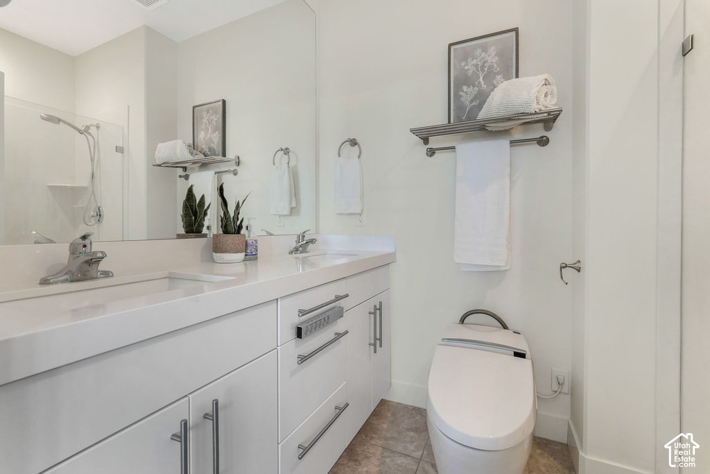 Bathroom featuring a dual vanity with white cabinetry, integrated sinks, and polished chrome fixtures