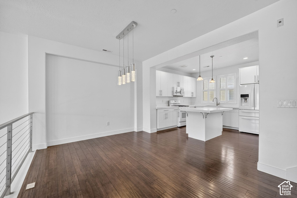 Open-concept living space featuring wood-finish flooring, a modern chandelier with multiple pendants, and a stainless steel cable railing