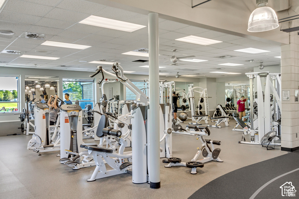 Fitness center featuring various exercise machines, suspended ceiling tiles with recessed lighting, and wall-mounted mirrors