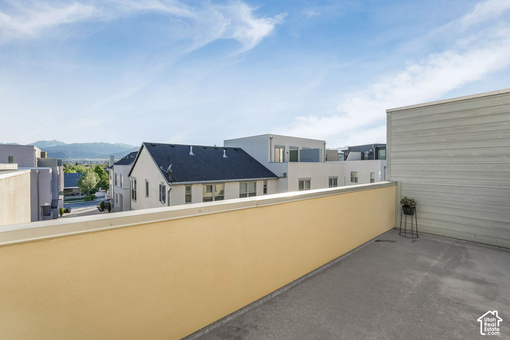 Rooftop patio featuring expansive concrete surfacing, a light yellow parapet wall, and an adjacent siding-clad wall