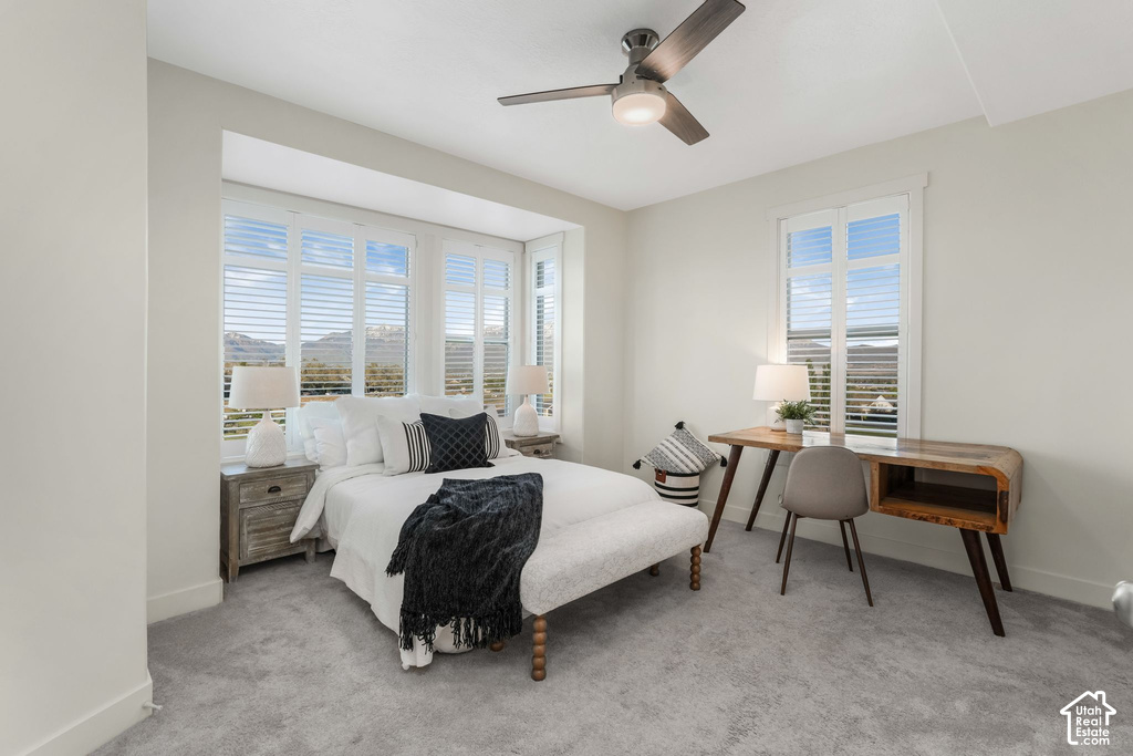Carpeted bedroom featuring a bay window with plantation shutters, a contemporary ceiling fan, and painted baseboards