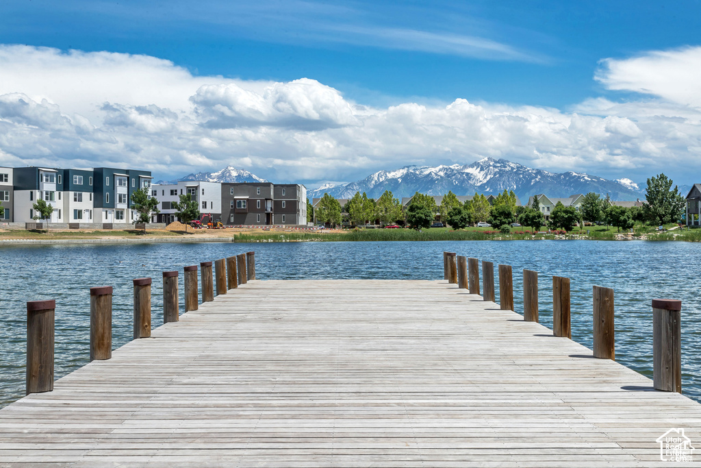 Wooden dock extending over a body of water, with snow-capped mountains in the background