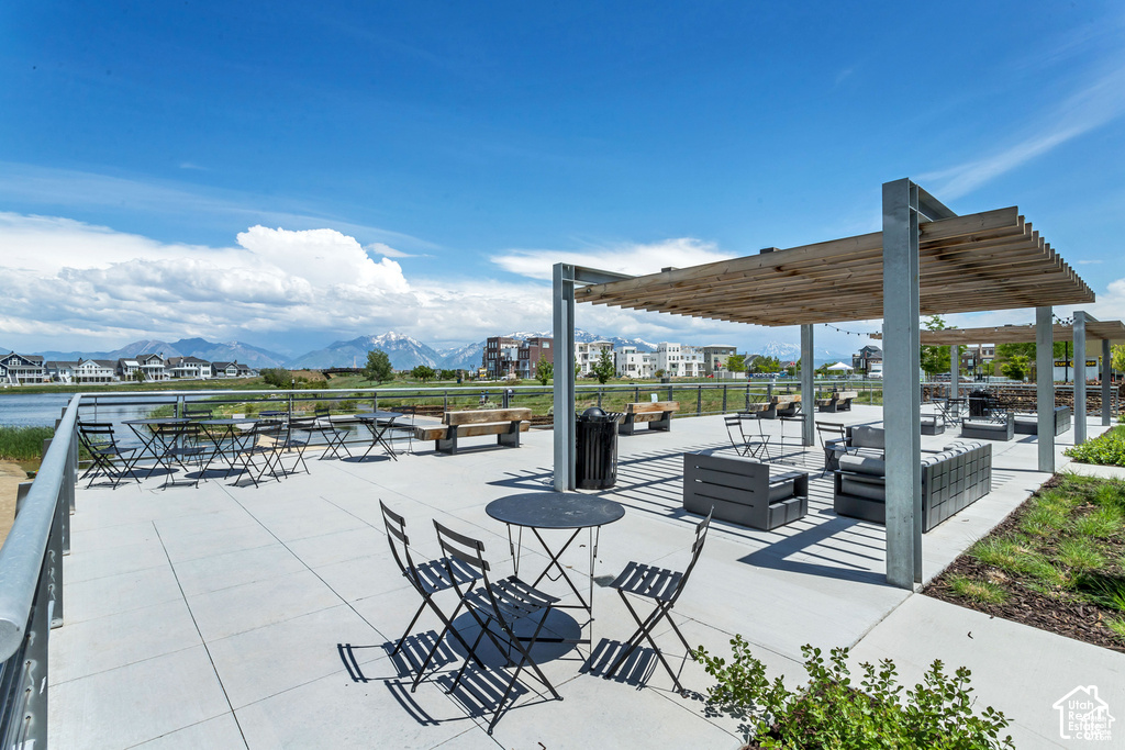Expansive outdoor common area featuring a large concrete patio, multiple pergolas with wood slat roofs, and a metal railing system
