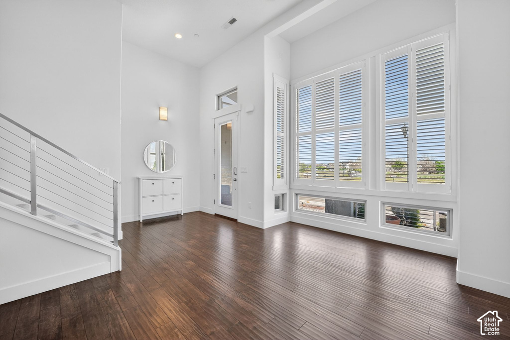 Expansive entry with rich wood-finish flooring, high ceilings, and a contemporary staircase featuring cable railing