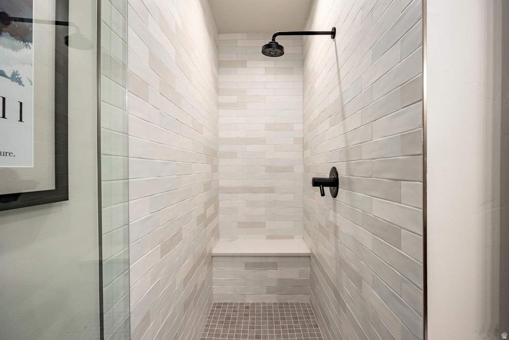 Walk-in shower featuring light-toned rectangular wall tiles, a built-in bench, and matte black fixtures
