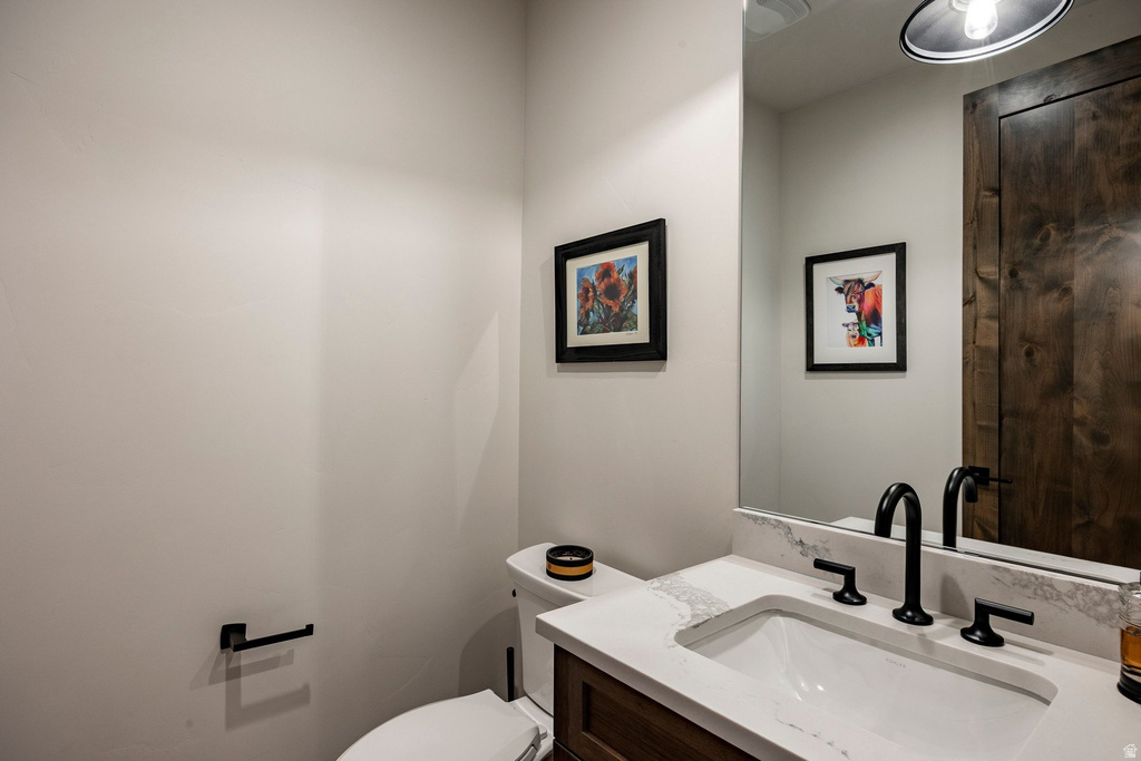 Bathroom featuring a wood-finish vanity with a white countertop and integrated sink, matte black faucet, and a large wall-mounted mirror