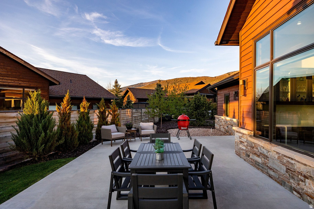 Spacious outdoor patio featuring a concrete surface, wood siding, stone veneer accents, and large picture windows