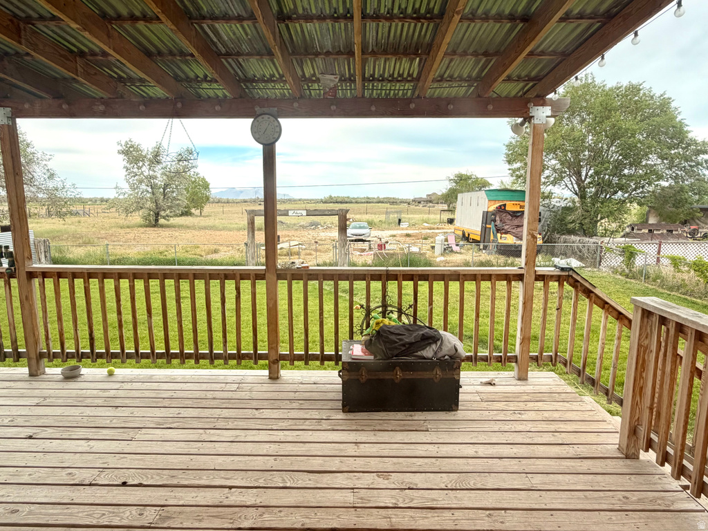 Expansive wooden deck featuring a slatted railing and a corrugated metal roof overhead