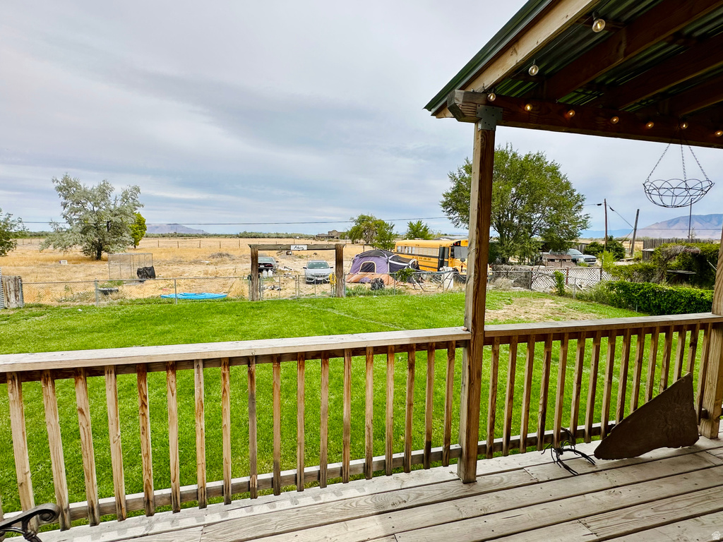 Wood deck with railing overlooking a green lawn and expansive natural landscape