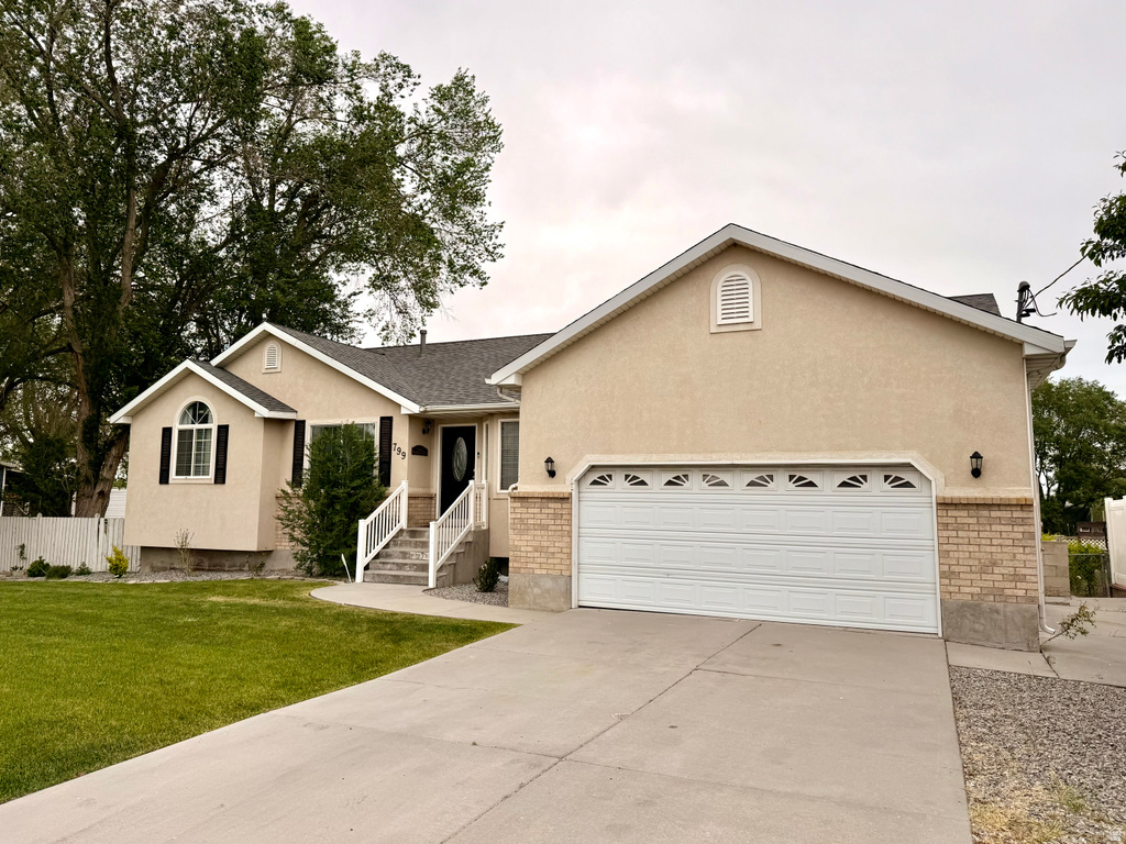 Stucco exterior featuring an attached two-car garage with brick detailing