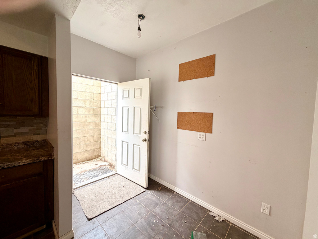 Kitchen area featuring dark wood-finish cabinetry, a patterned backsplash, and a granite-style countertop