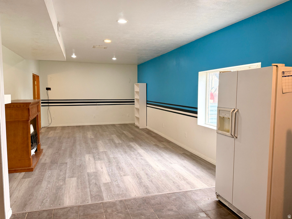 Spacious room featuring wood-finish flooring, a decorative fireplace mantel, recessed ceiling lighting, and a brightly painted accent wall