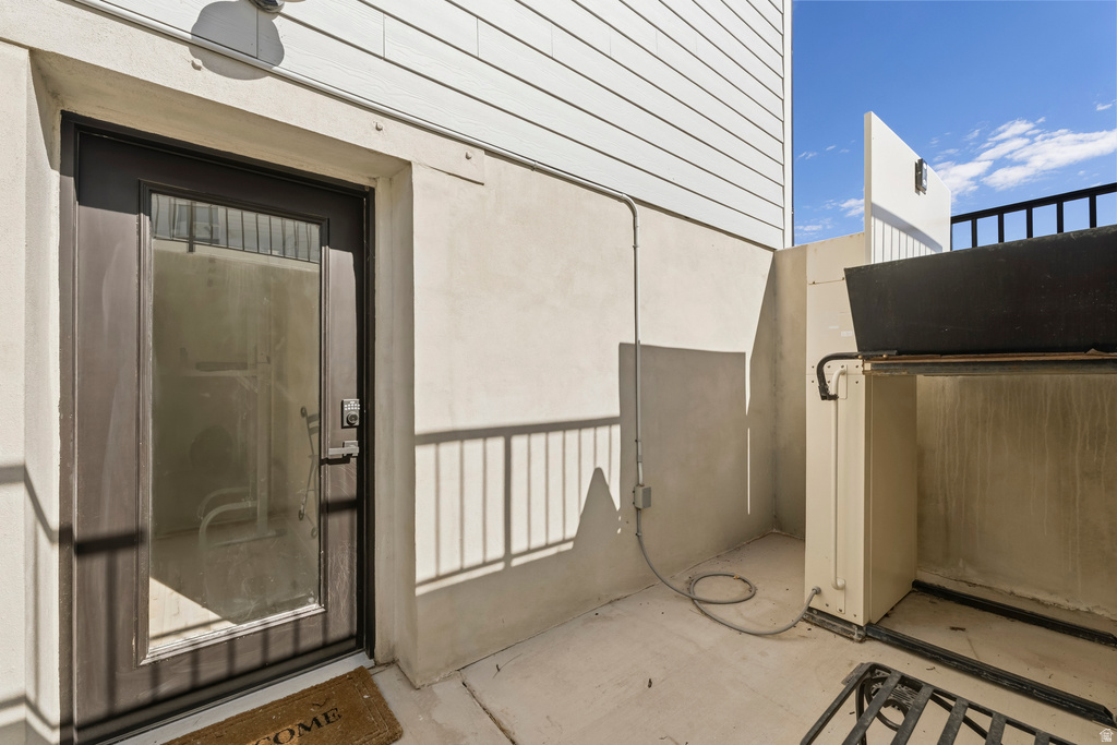 Private outdoor patio area featuring a stucco wall, white horizontal siding, and a dark-framed glass paneled door