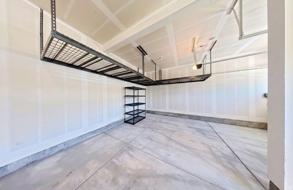 Spacious garage featuring concrete flooring and exposed ceiling rafters