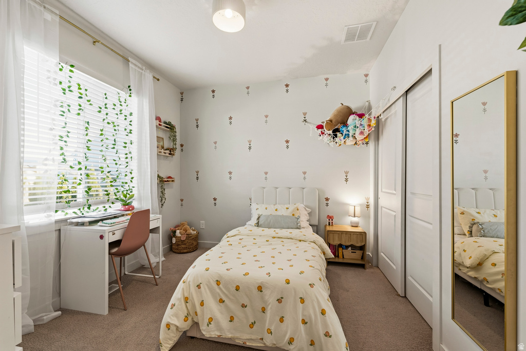 Bedroom featuring neutral carpeting, a built-in desk, a window with blinds, and white bi-fold closet doors