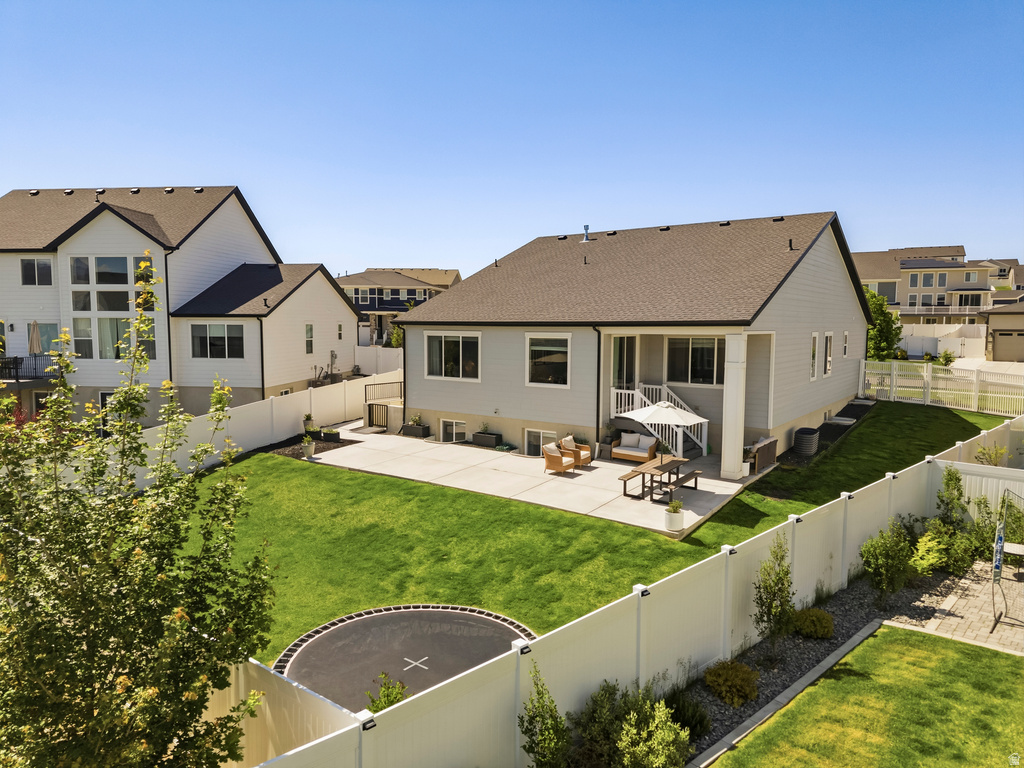 Expansive rear yard featuring a concrete patio, grassy lawn, and white privacy fencing