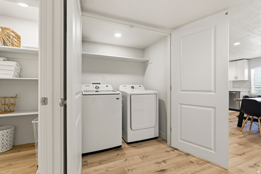 Dedicated laundry area featuring a washer and dryer, recessed lighting, and upper shelving