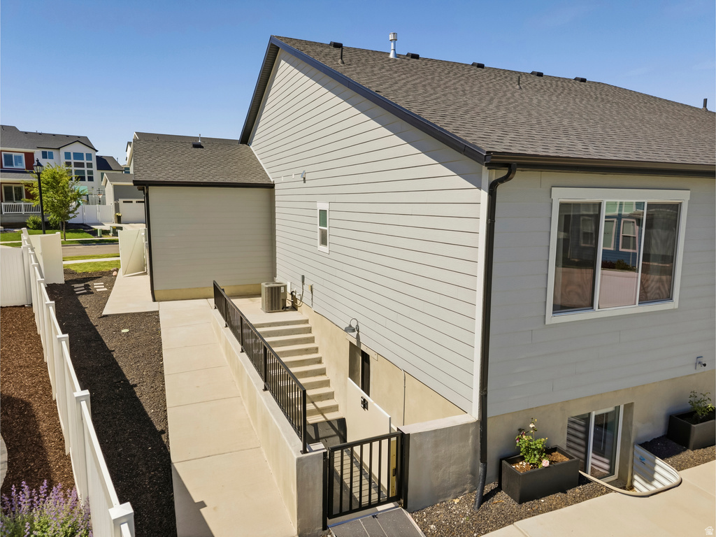 Exterior of the property featuring light grey siding and a dark shingle roof