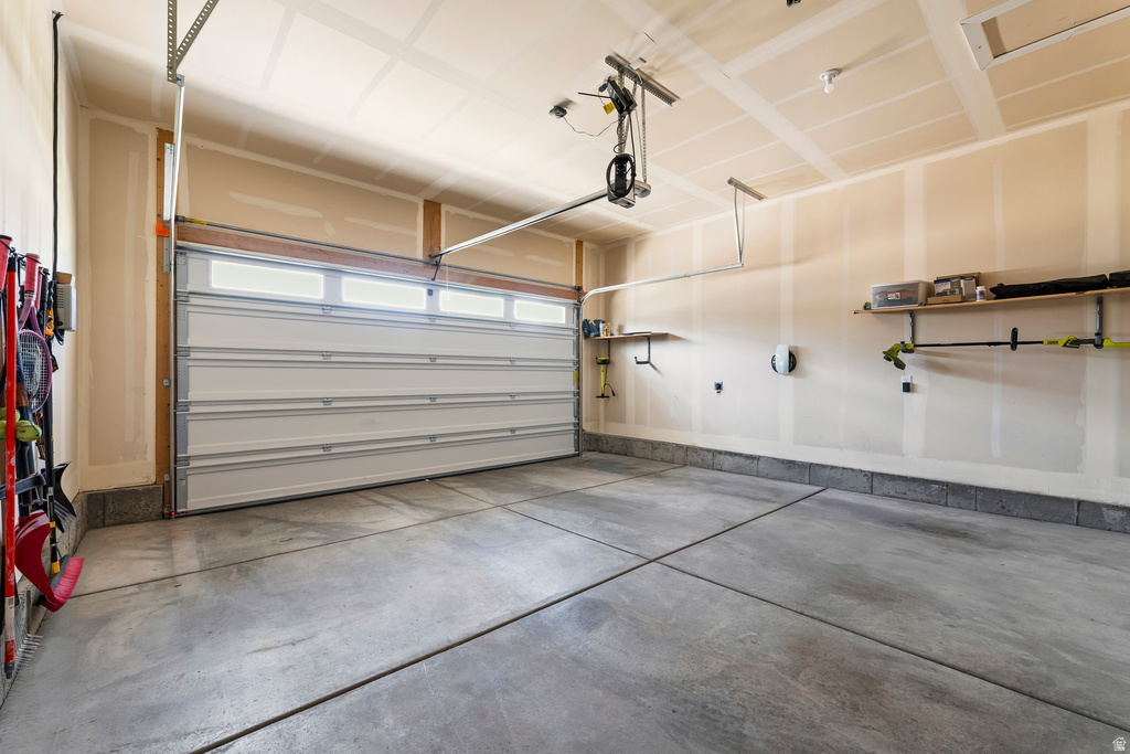 Spacious garage featuring a concrete floor, an overhead door with upper window panels, and integrated shelving