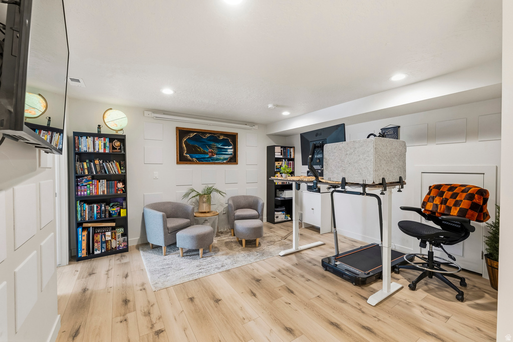 Spacious room featuring light wood-finish flooring, recessed lighting, and white paneling