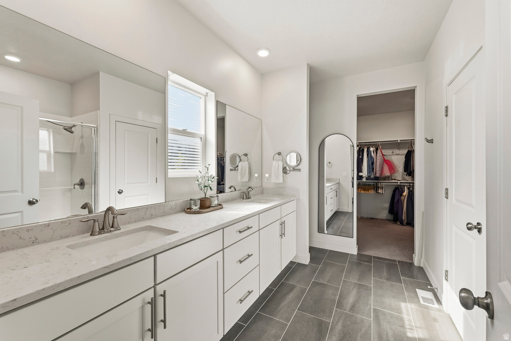 Spacious bathroom featuring a dual vanity with light-toned countertops, white cabinetry, and a large mirror