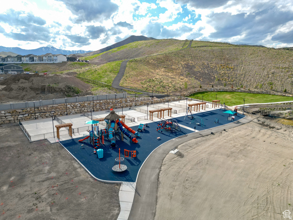 Community recreational area featuring a large playground with multiple slides, swings, and climbing structures on a blue soft-fall surface
