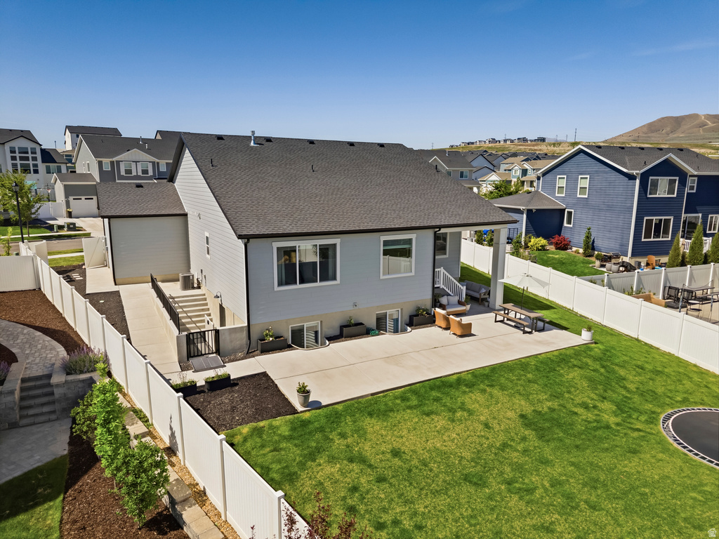Expansive backyard featuring a large concrete patio, manicured lawn, and white privacy fencing
