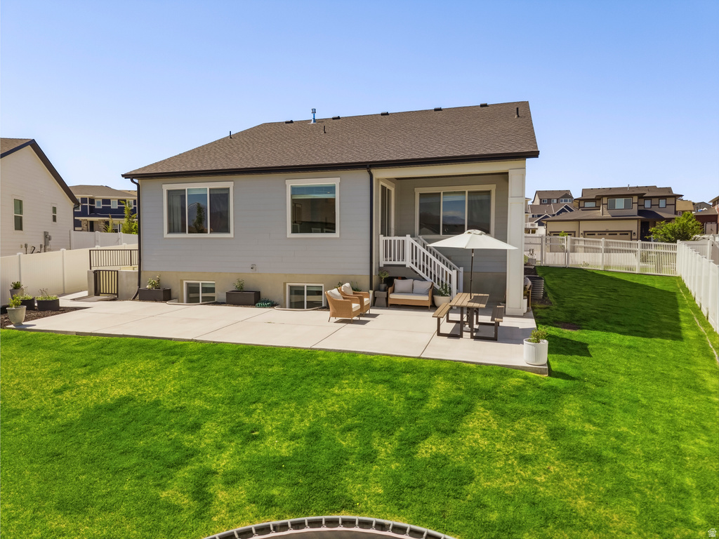 Expansive backyard featuring a large concrete patio, a manicured lawn, a white privacy fence, and a staircase leading to a lower-level concrete area