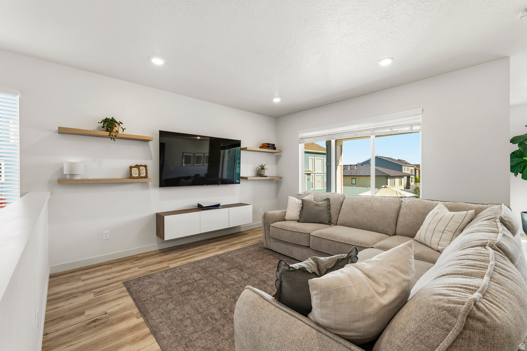 Living area featuring wood-finish flooring, recessed lighting, a built-in media console, and a large window