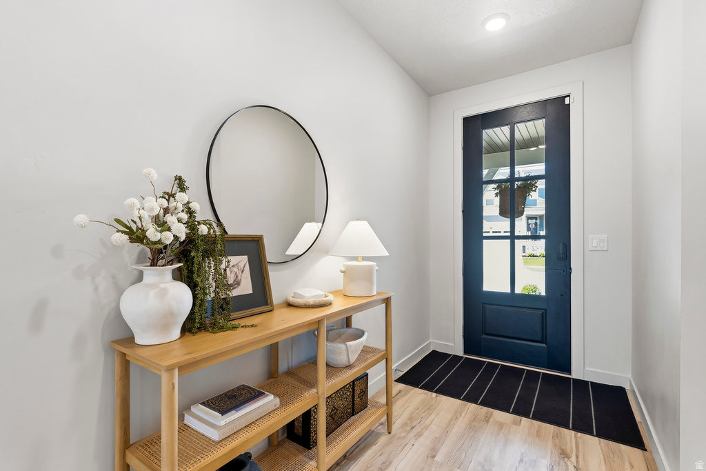 Entryway featuring a dark paneled door with multiple glass panes, light wood-finish flooring, recessed ceiling lighting, and crisp white walls