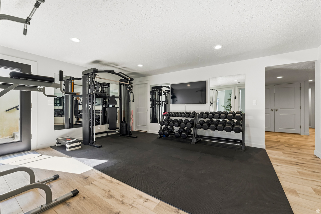 Dedicated fitness space featuring rubberized flooring, recessed lighting, and mirrored wall accents