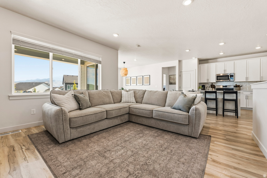 Open-concept living area with a large window, recessed lighting, and wood-finish flooring