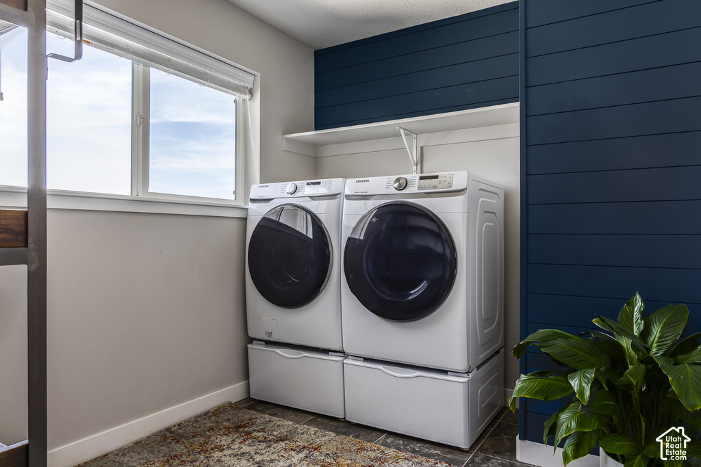 Laundry area featuring modern front-loading washer and dryer, a functional shelving unit, and an accent wall with horizontal paneling