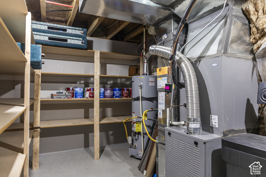 Utility area featuring a water heater, furnace, and extensive built-in wooden shelving for organized storage