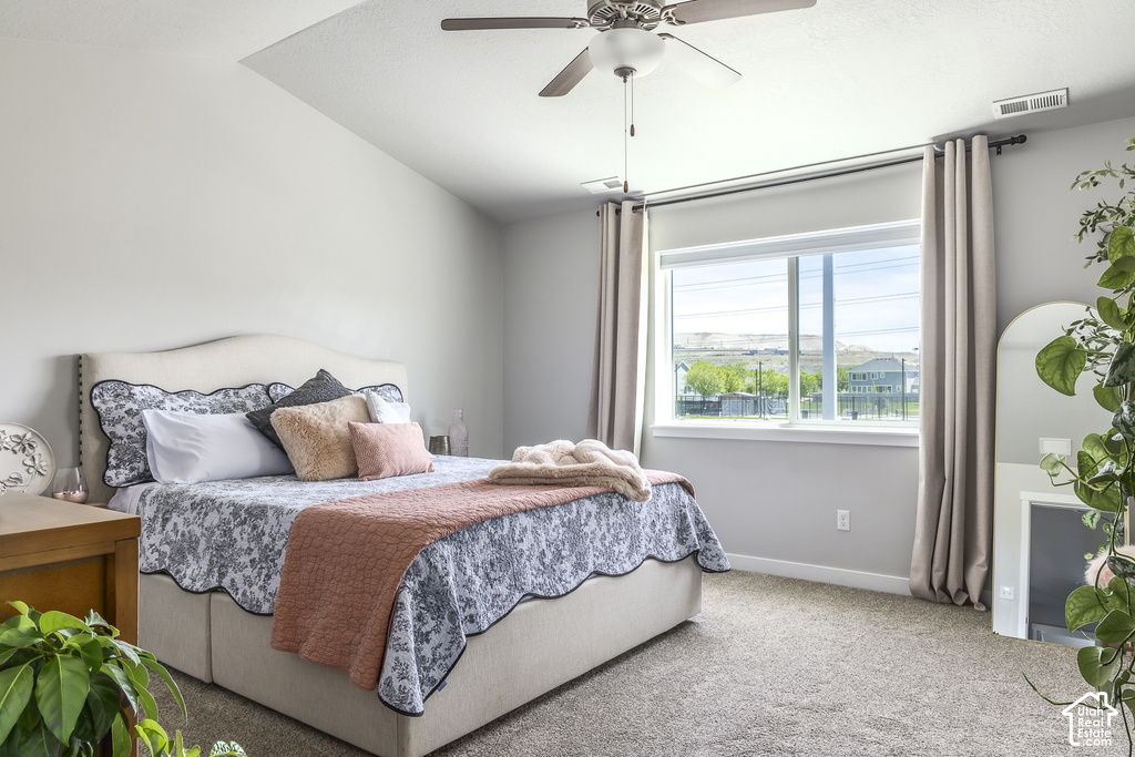 Vaulted ceiling with a ceiling fan, large window with outdoor views, light gray walls, and carpet flooring
