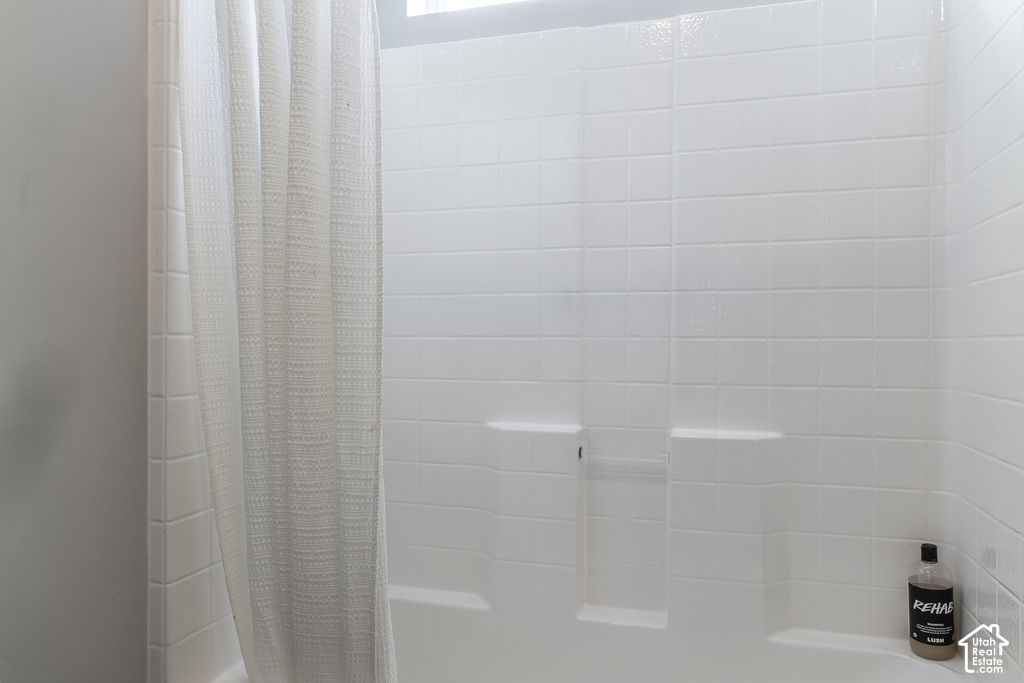 White subway tile surround with integrated soap dish and shelf, above a white tub