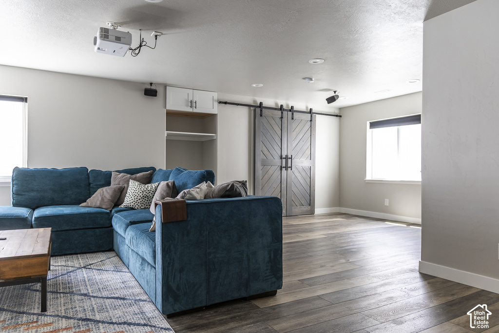 Spacious room featuring wood-finish flooring, recessed lighting, and a mounted projector