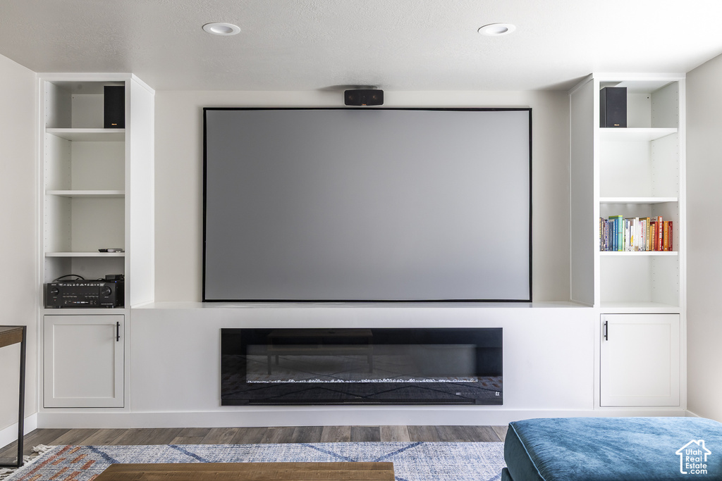 Integrated media wall featuring a large screen, built-in electric fireplace, and white cabinetry
