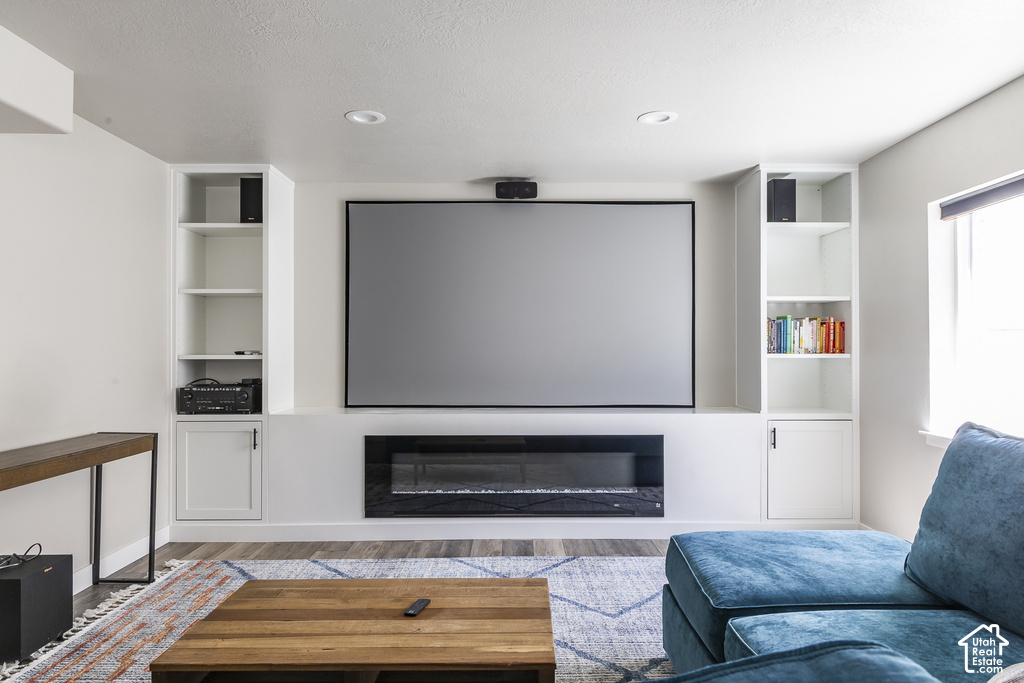 Integrated media wall featuring a large projection screen, built-in electric fireplace, and recessed lighting