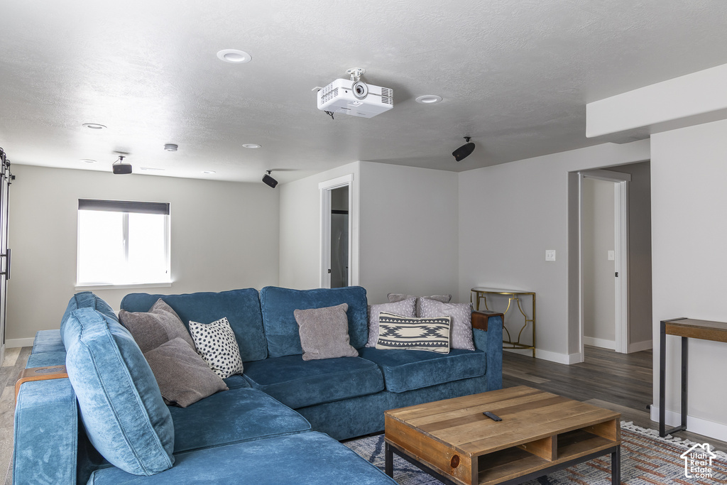 Recreation room featuring recessed lighting, a ceiling-mounted projector, wall-mounted speakers, and wood-finish flooring