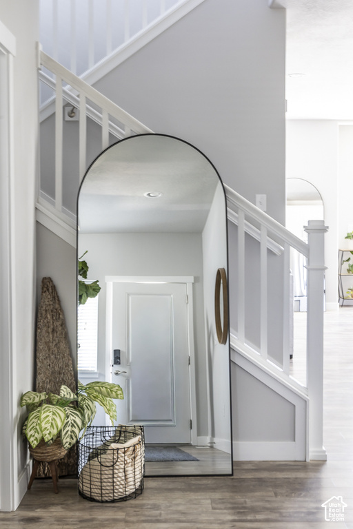 Entryway featuring wood-finish flooring, white painted baseboards, and a staircase with white balusters