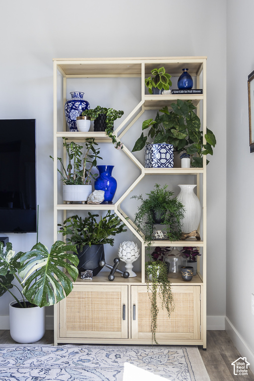 Light wood-finish shelving unit featuring varied geometric compartments and two lower rattan-front cabinets with dark hardware