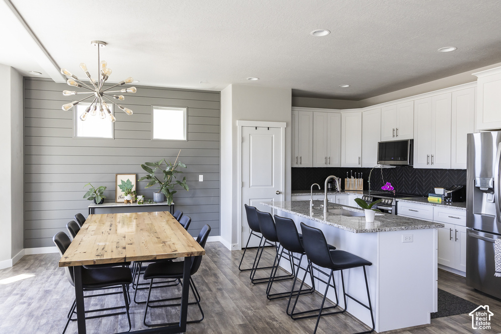 Open-concept kitchen and dining area featuring wood-finish flooring, recessed lighting, and a modern chandelier