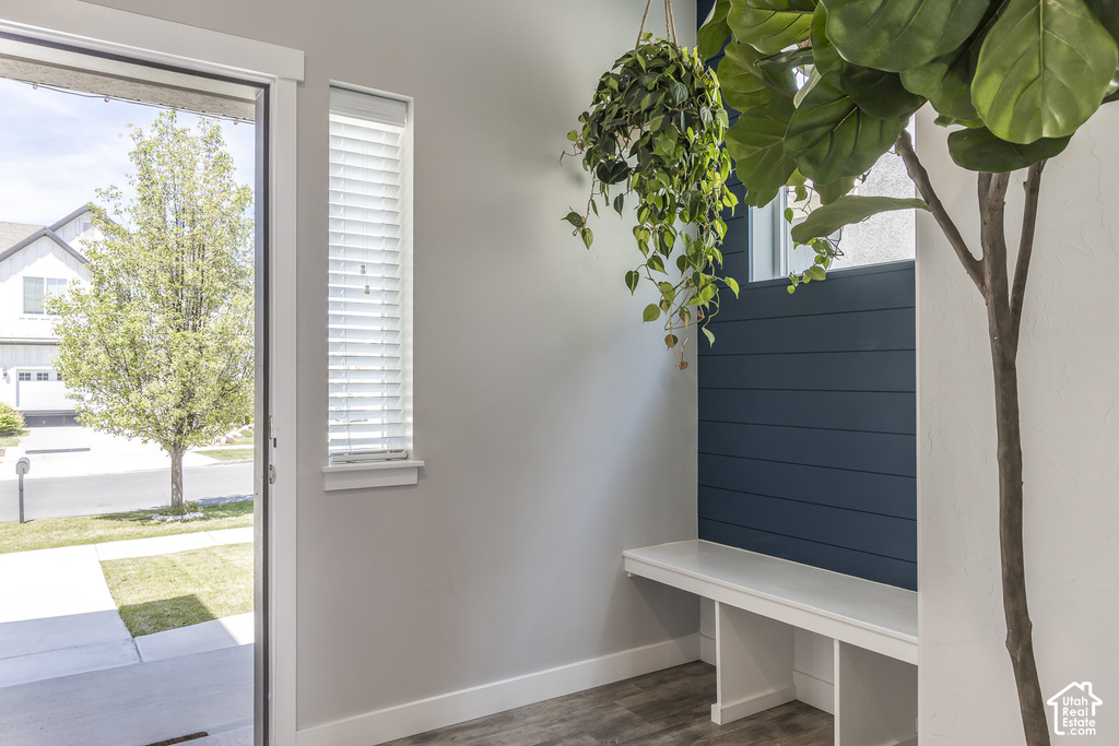 Entryway featuring wood-finish flooring, a built-in bench with storage, and vertical slat wall paneling