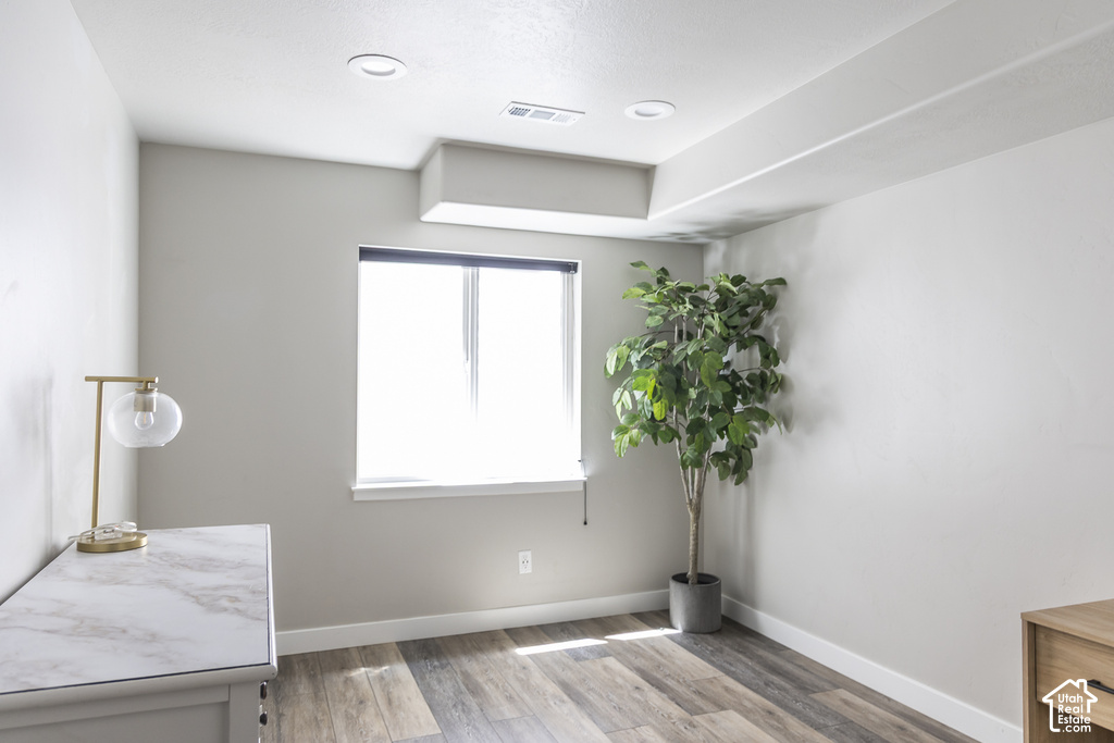 Bright interior space featuring a window with blinds, wood-finish flooring, recessed lighting, and crisp white baseboards