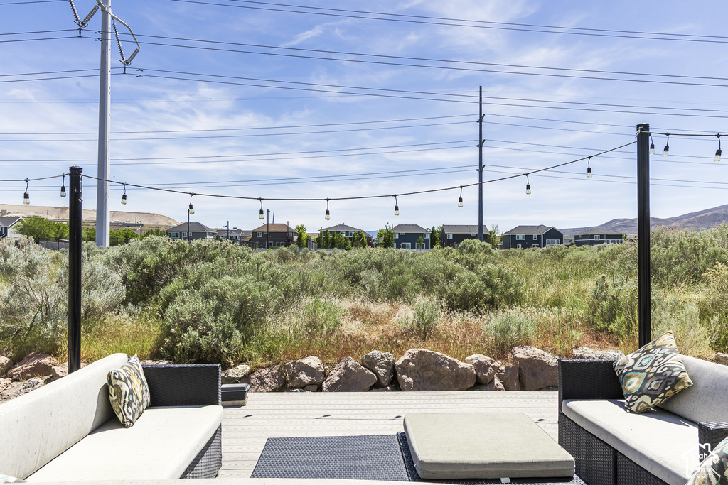 Outdoor deck with string lighting, surrounded by natural landscaping and decorative boulders