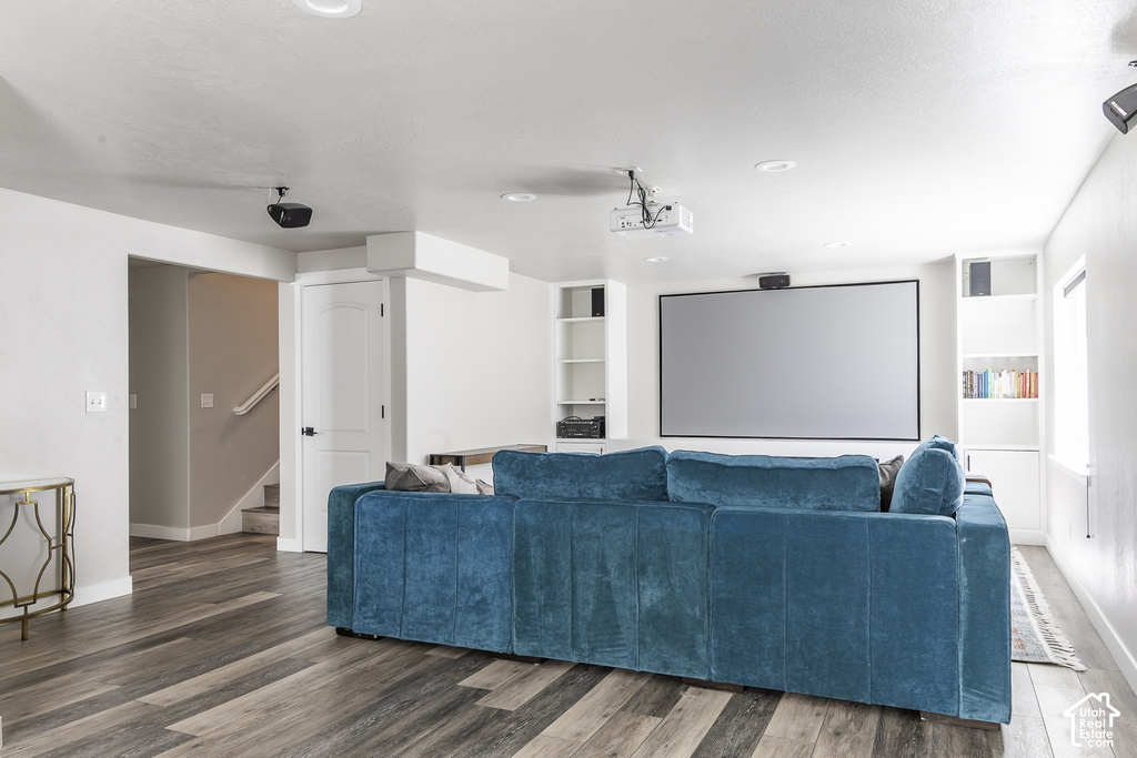 Entertainment space featuring a large projection screen, built-in shelving, wood-finish flooring, and recessed lighting