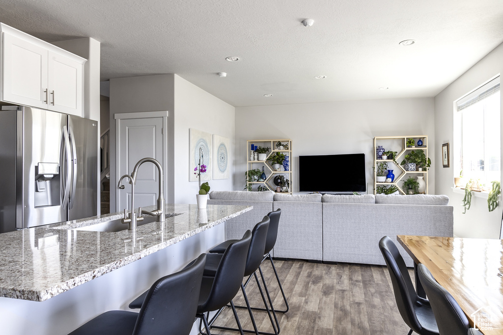 Open-concept living space featuring a granite-finish kitchen island with an undermount sink and a gooseneck faucet