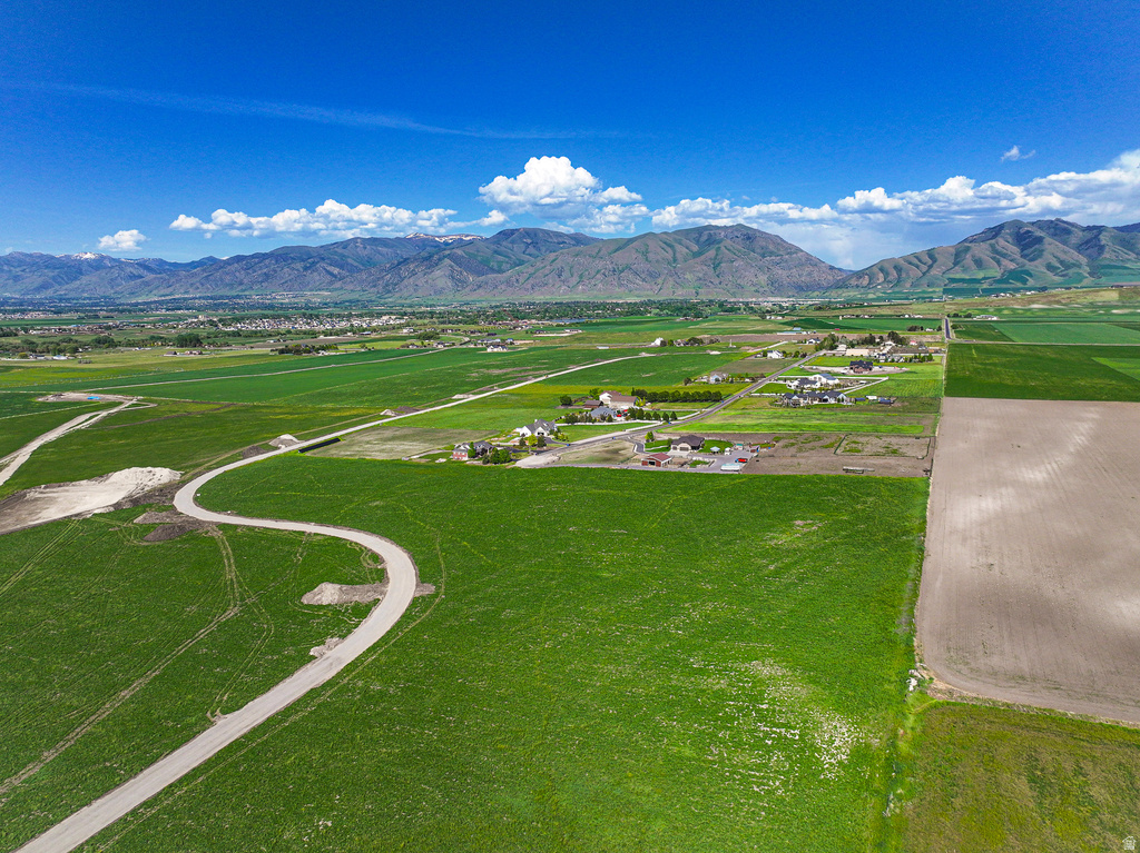 Expansive green land with a winding paved road, surrounded by agricultural fields and distant mountains