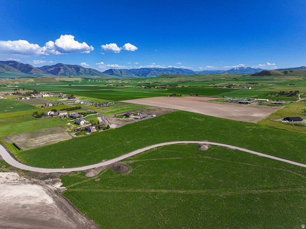 Expansive green fields and cultivated land with distant mountain ranges under a clear blue sky